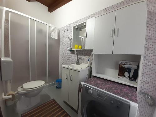 a bathroom with a toilet and a sink and a washing machine at TONNARA HOUSE AND HOLIDAY in Avola