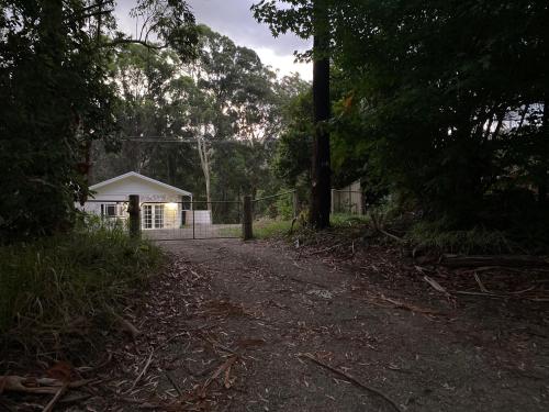 a house with a fence and a dirt road at Korora Hideaway in Coffs Harbour