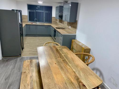 a kitchen with a wooden table and a refrigerator at M4M Rooms- NG8 5NP Room 1 in Nottingham
