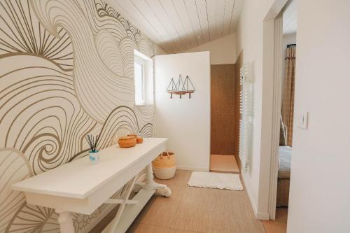 La salle de bains est pourvue d'une table blanche et d'un mur à motifs de vagues. dans l'établissement Villa Dune, au Bois-Plage-en-Ré
