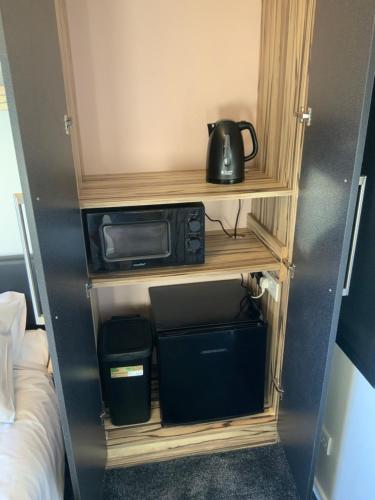 a small room with a microwave on a shelf at The Nest - Cosy Rooms in Harwood