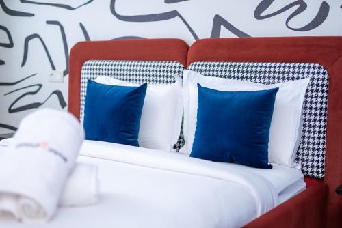 a red and white bed with blue pillows at The lodge Residence by Goodmove - Hay Riad in Rabat