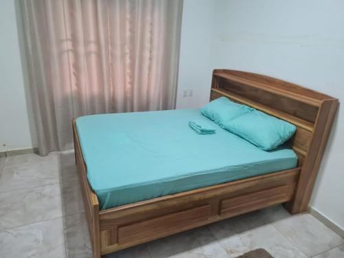 a bed with a wooden frame and blue pillows on it at Vakantiewoning Tout lui faut in Wanica