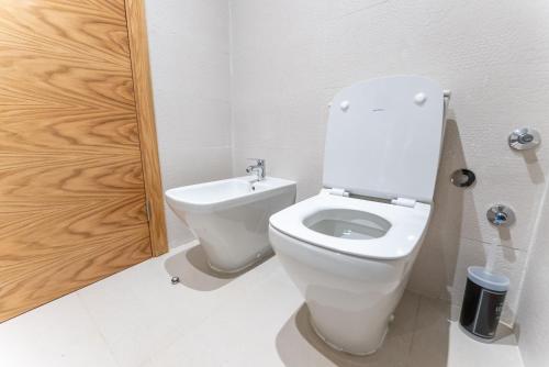 a white toilet in a bathroom with a wooden door at The lodge Residence by Goodmove - Hay Riad in Rabat