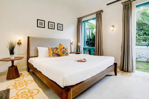 a bedroom with a large bed and a window at Valencia By DanCenter - 3 Bhk Villa in Siolim in Siolim
