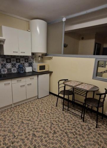 une cuisine avec des armoires blanches et une table et des chaises dans l'établissement Studio IRIS type T1, à Évaux-les-Bains