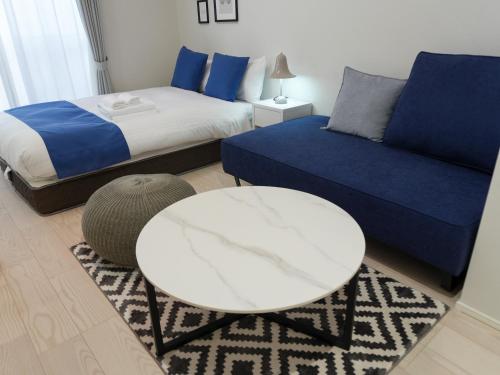 a bedroom with a bed and a white table and a couch at OUCHI HOTEL Onaganishi in Hiroshima