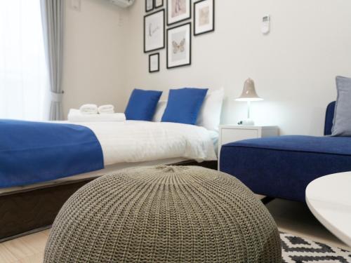 a bedroom with two beds and a ottoman at OUCHI HOTEL Onaganishi in Hiroshima
