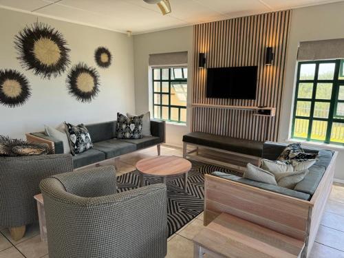 a living room with couches and a flat screen tv at Settler Sands - Holsboer Vacations in Port Alfred