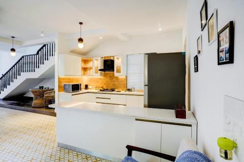 a kitchen with white cabinets and a black refrigerator at Valencia By DanCenter - 3 Bhk Villa in Siolim in Siolim