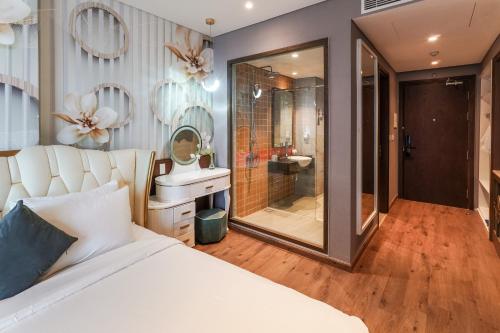 a bedroom with a large white bed and a bathroom at Apec Mandala Mũi Né Resorts & Hotels NN in Phan Thiet
