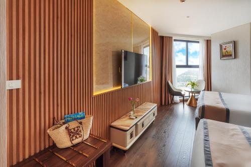 a hotel room with a bed and a flat screen tv at Apec Mandala Mũi Né Resorts & Hotels NN in Phan Thiet