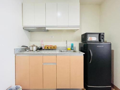 a kitchen with a black refrigerator and a microwave at The Palladium Retreat in Iloilo City