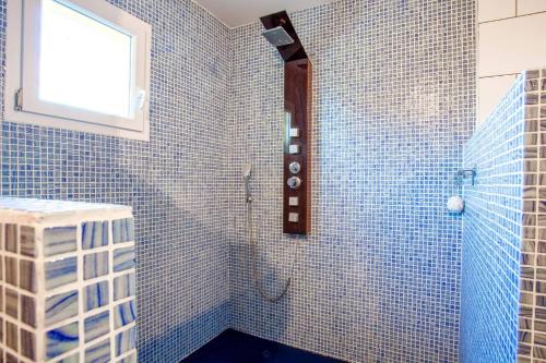 La salle de bains est pourvue de carrelage bleu, d'une douche et d'une fenêtre. dans l'établissement Villa Grenache by Villa Plus, à Usclas-lʼHérault