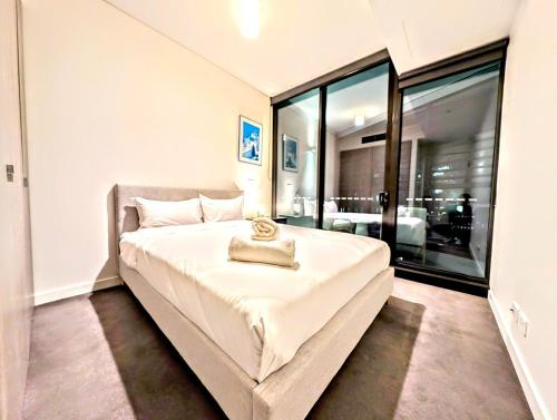 a bedroom with a large white bed with a large window at Luxurious &cozy apartment with pool and gym in Sydney CBD in Sydney