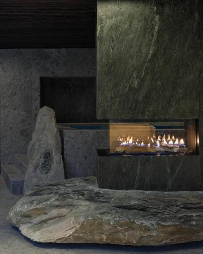 a fireplace with a large rock next to it at Lodge Park in Megève