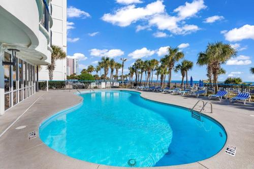 a swimming pool with palm trees and the ocean at Boardwalk Resort Beachfront Condos in Myrtle Beach
