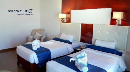 a room with three beds with blue and white sheets at Golden Tulip Headington in Muscat