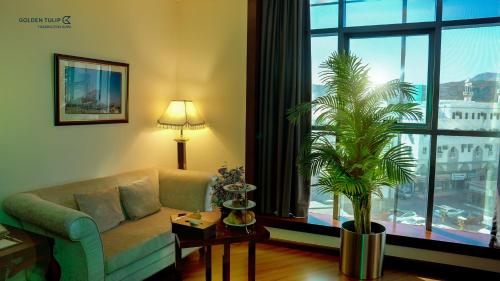 a living room with a couch and a potted plant at Golden Tulip Headington in Muscat