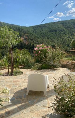 a white chair sitting on a stone patio with flowers at Quinta do Brejo in Vila Cova à Coelheira