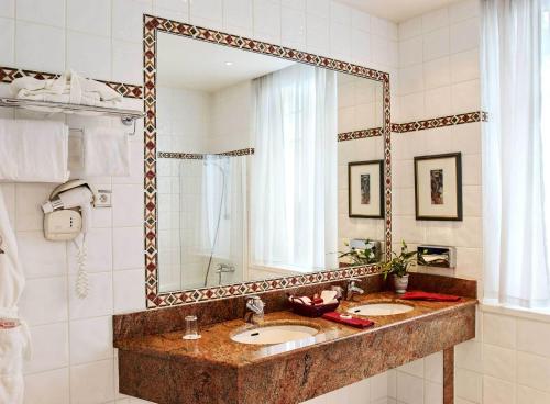 a bathroom with two sinks and a large mirror at Hotel De La Matelote in Boulogne-sur-Mer