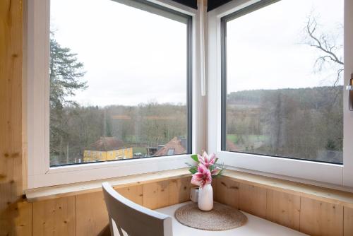 a vase of flowers sitting on a table in front of a window at Refugium aus Vollholz in Schlitz
