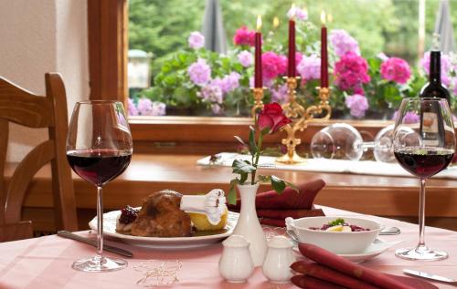 a table with a plate of food and two glasses of wine at Waldhotel Rennsteighof in Bad Liebenstein