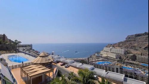 a view of a resort with a pool and the ocean at Sunny Seaview Modern apt - pool and beach access in Taurito