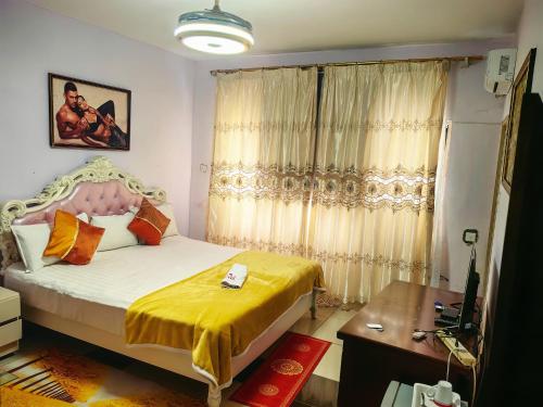 a bedroom with a bed with yellow sheets and a window at Hongyuan Premier hotel in Accra
