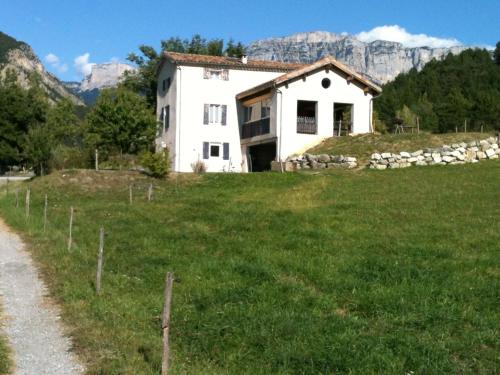 a white house in a field with mountains in the background at Gîte d'étape d'Aurouses in Die