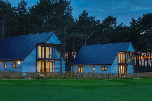 a house with a blue roof on a field at Le Strange Arms Garden Lodges in Hunstanton