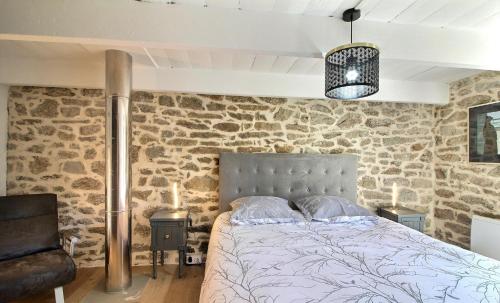 a bedroom with a bed and a stone wall at Ty Chann Rouz in Ile de Sein