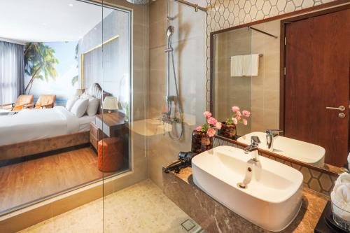 a bathroom with a sink and a shower and a bed at Apec Mandala Mũi Né Resorts & Hotels NN in Phan Thiet