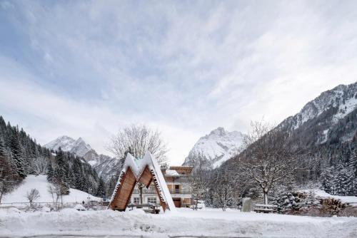 a building covered in snow with mountains in the background at Guesthouse Canazei Cozy 2-Bedrooms in Canazei
