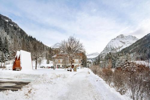 a snow covered street with a building and mountains at Guesthouse Canazei Cozy 2-Bedrooms in Canazei