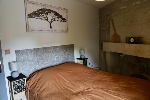 - une chambre dotée d'un lit avec une photo d'arbre sur le mur dans l'établissement Gîte - petite maison proche du Futuroscope, à Beaumont