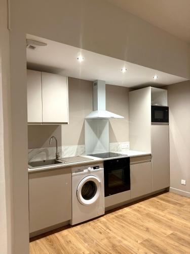 une cuisine avec une machine à laver et un évier dans l'établissement Le Cosmo, à Boulogne-sur-Mer