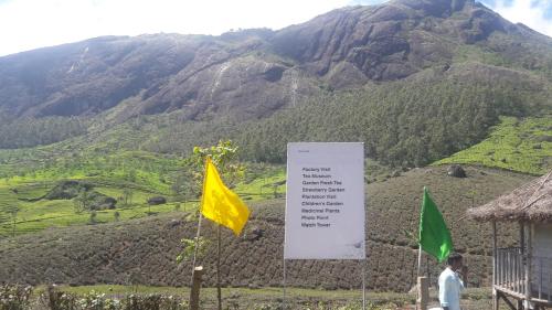 a sign and two flags in front of a mountain at The Tea Leaf Cottage in Munnar