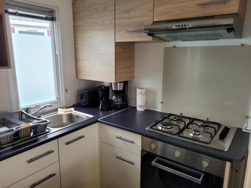 Il comprend une petite cuisine équipée d'une cuisinière et d'un évier. dans l'établissement VM-Mobile Home 3 ch, 2 sdb, Convivialité, détente et confort, en famille ou entre amis, à Lattes