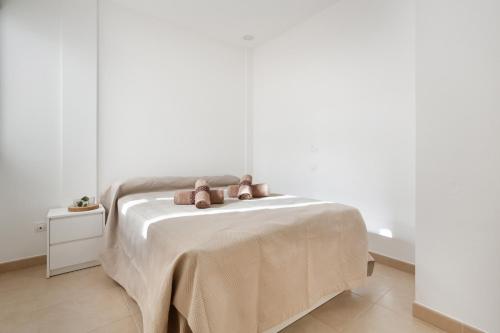 a white bedroom with a bed with two brown pillows at Casa Castilla in Puerto del Rosario