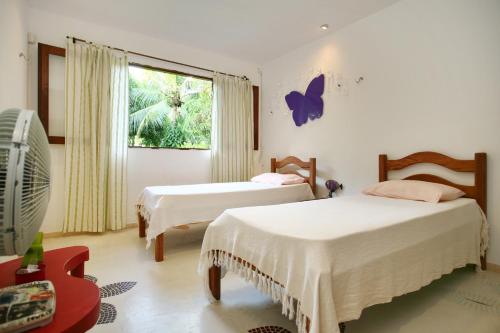 um quarto com duas camas e uma borboleta na parede em Toca do Jacaré em Granja Beira Mar