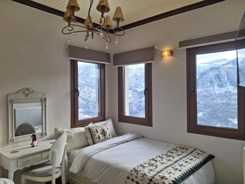 a bedroom with a bed and a desk and windows at Αγνάντι in Metsovo
