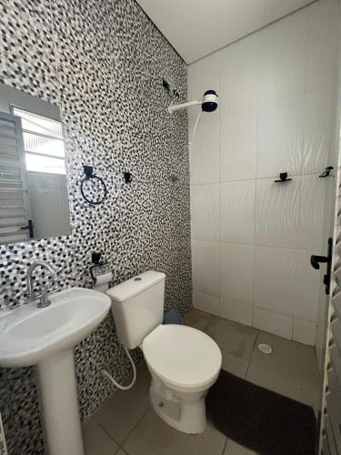 a bathroom with a toilet and a sink at Vila Mar Suítes in Bertioga