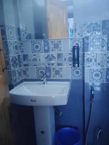 a bathroom with a sink and blue and white tiles at Little italy pulga in Kalgha