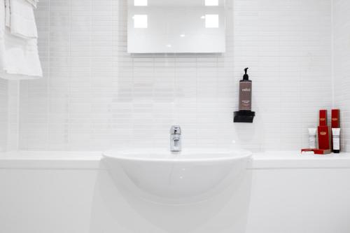 a white bathroom with a sink and a soap dispenser at Muthu Glasgow River Hotel in Erskine