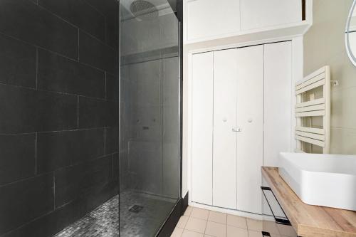 La salle de bains est pourvue d'une douche et d'un lavabo blanc. dans l'établissement L'Alegria - Paris - Marais - 4 prs, à Paris