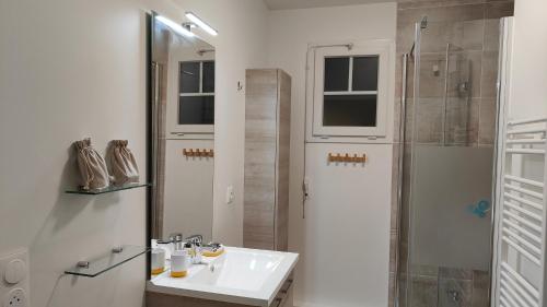 une salle de bain blanche avec un lavabo et une douche dans l'établissement Magnifique appartement climatisé 70 m2, Grande terrasse 42 m2, classé 4 étoiles, à Andernos-les-Bains