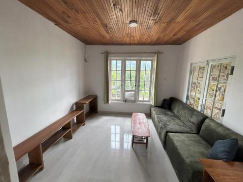un salon avec un canapé vert et une fenêtre dans l'établissement HnM Kandy - Peradeniya Small Apartment with a luxury bed, kitchen, living area, attached washroom, à Angunawala