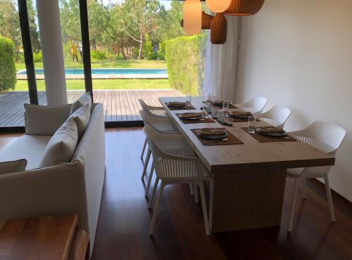 a dining room with a wooden table and chairs at Tróia Beach Pool & Golf in Grândola