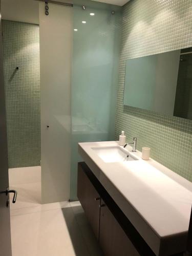 a bathroom with a sink and a shower with a mirror at Tróia Beach Pool & Golf in Grândola